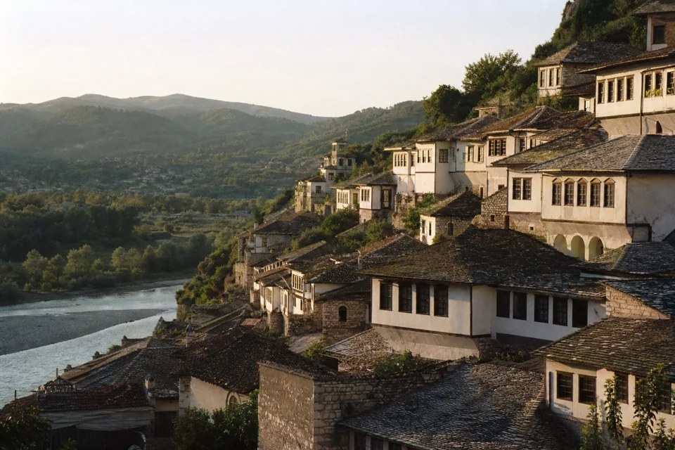 White houses with stone roofs on a steep slope above a river valley in Albania
