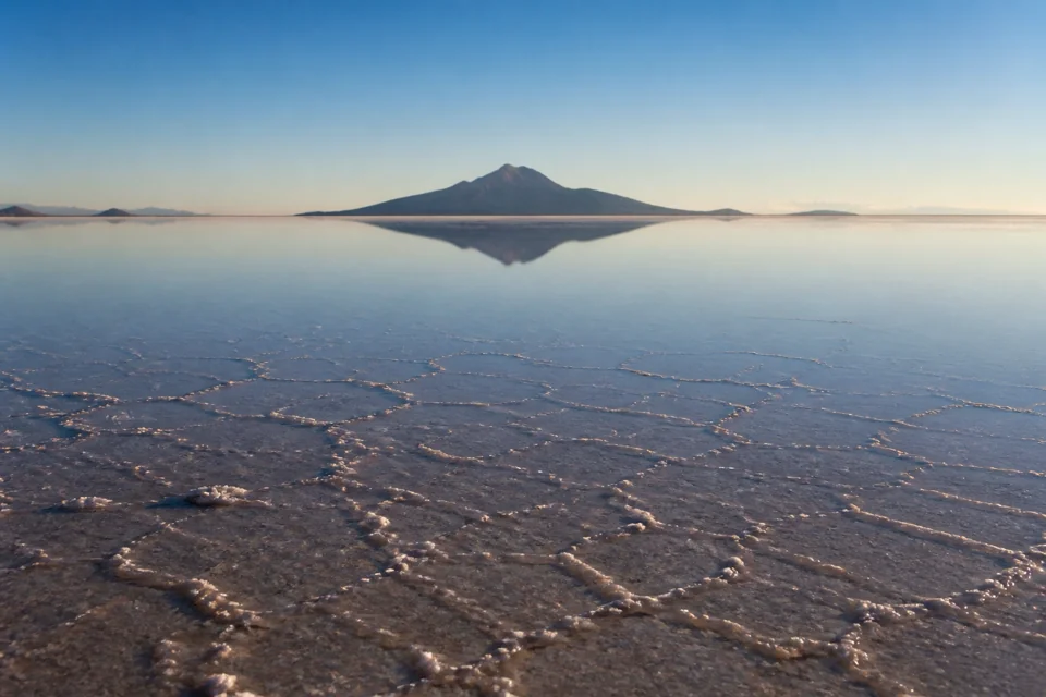 A wide white salt flat mirroring the sky after shallow rain in Bolivia