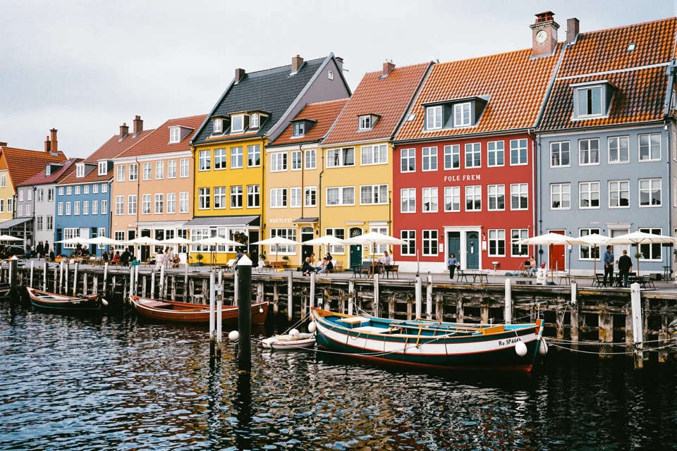 Wooden boats moored in a harbour lined with colourful houses in Denmark
