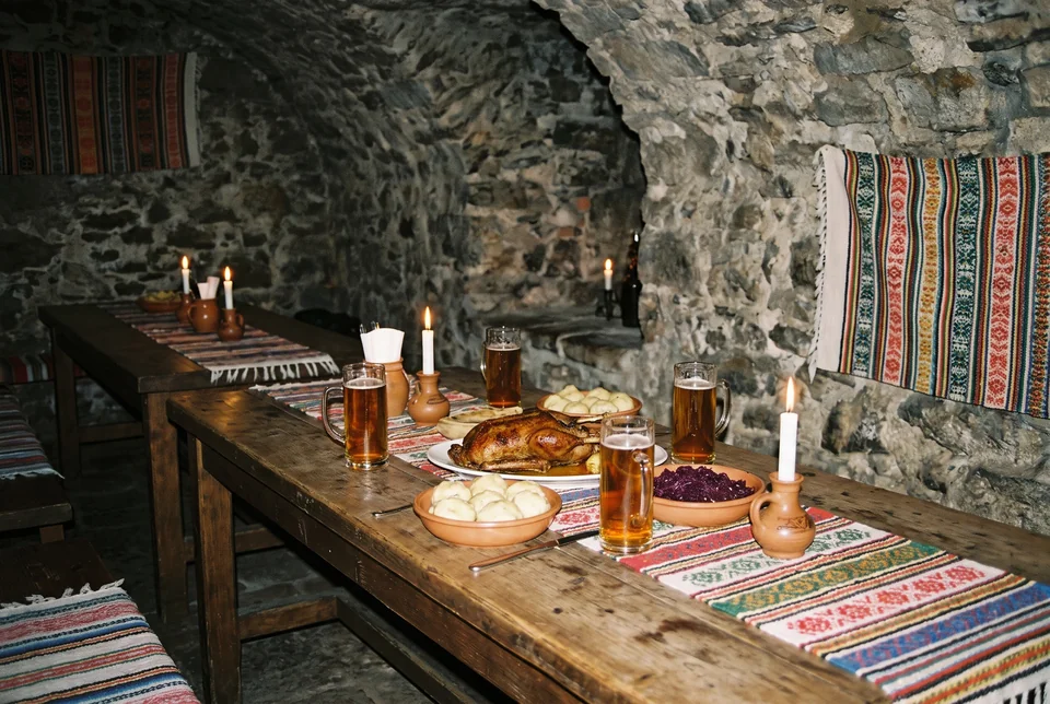 Traditional Czech table with beer, roast duck and candles in a stone cellar in Prague, visualization