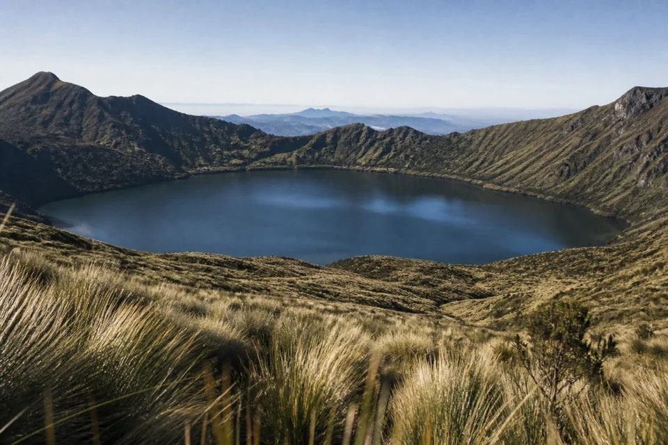 A crater lake ringed by high páramo grassland glinting on a cold morning in Ecuador