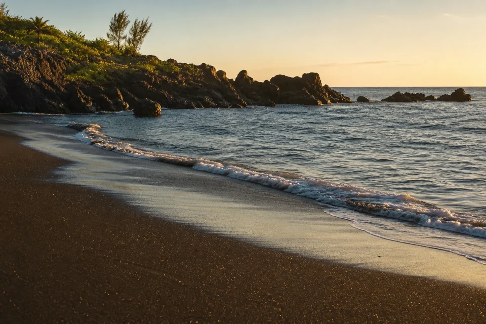 Waves breaking on a black sand beach among volcanic rocks in El Salvador