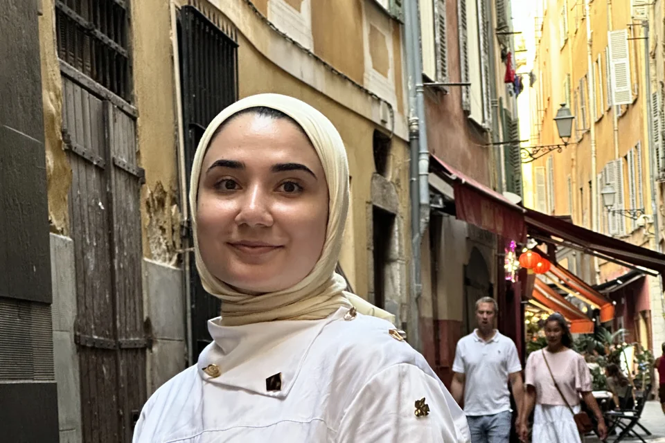 Traveller in a narrow old-town lane in France, ochre facades and shop awnings on both sides