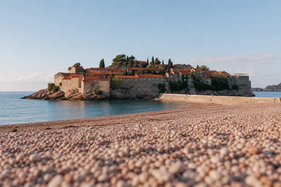 A rocky islet of stone houses linked to shore by a thin sand strip in Montenegro