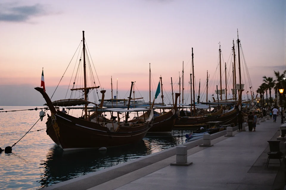 Wooden boats moored along a seafront road at dusk in Qatar