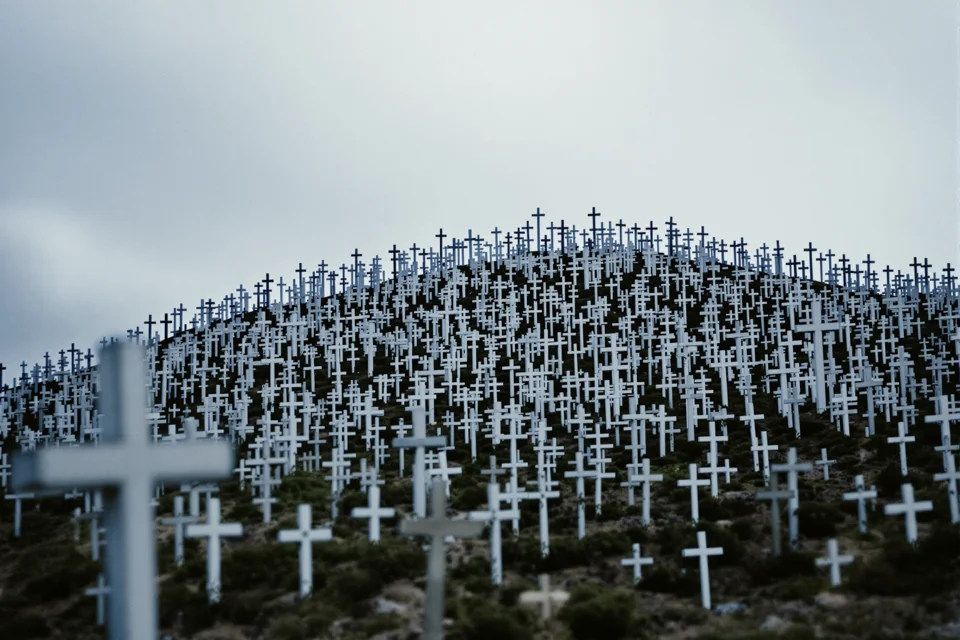 A hill in Lithuania under a grey sky covered with thousands of small crosses