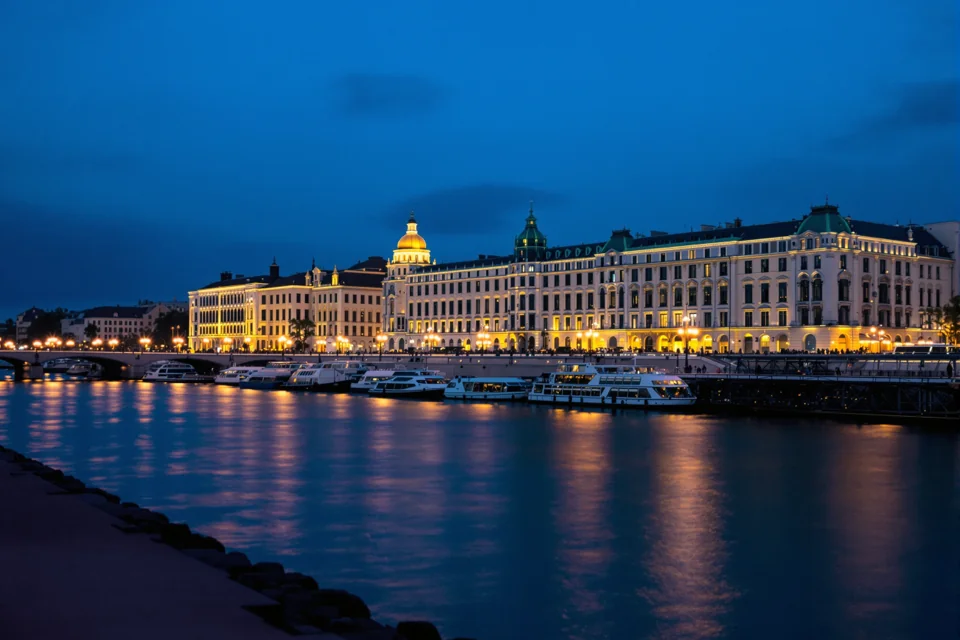 Grand stone facades along the river in Hungary glowing with light at blue hour