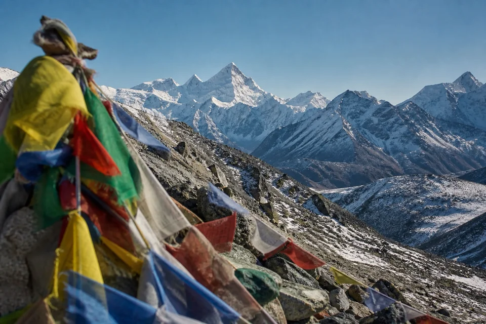 Nepal'de yüksek sırtta dua bayrakları karlı zirvelerin önünde dalgalanıyor
