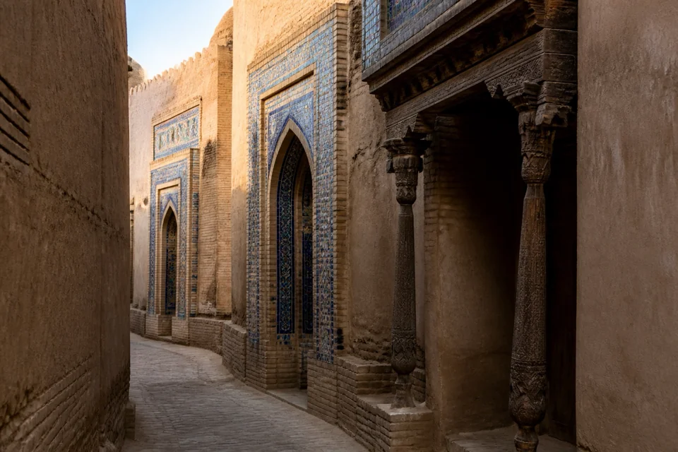 Blue tiled doors along a narrow mudbrick street in morning light in Uzbekistan