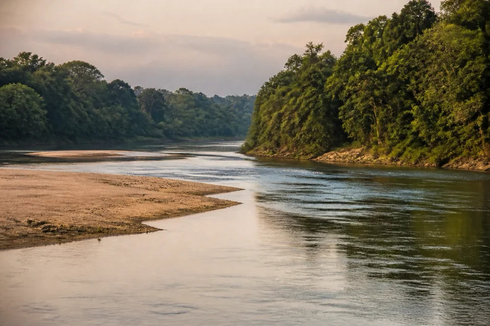 The sandbanks of a wide river reaching wooded shores in evening light in Paraguay
