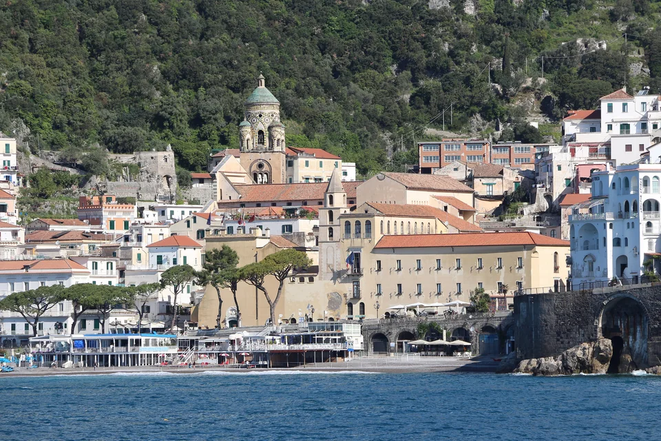The domed bell tower, waterfront houses and green slopes seen from the sea at Amalfi
