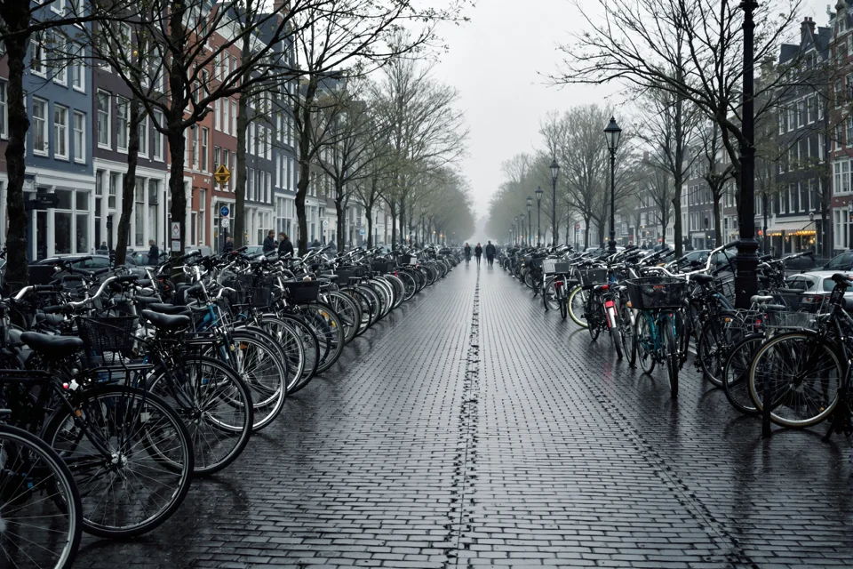Hundreds of bicycles parked one after another on rain-soaked cobbles in Amsterdam