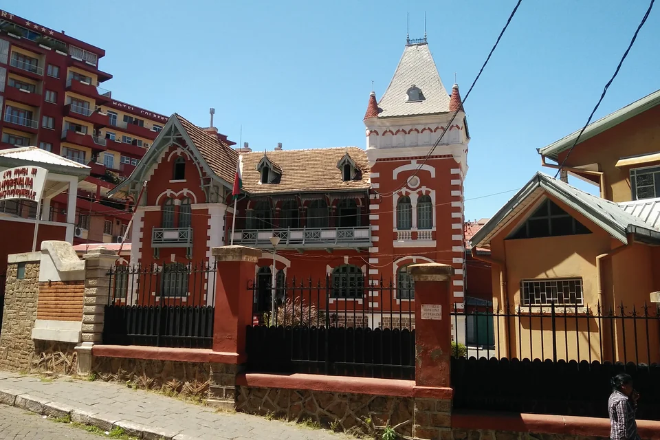 A towered historic red-brick building behind an iron fence in Antananarivo