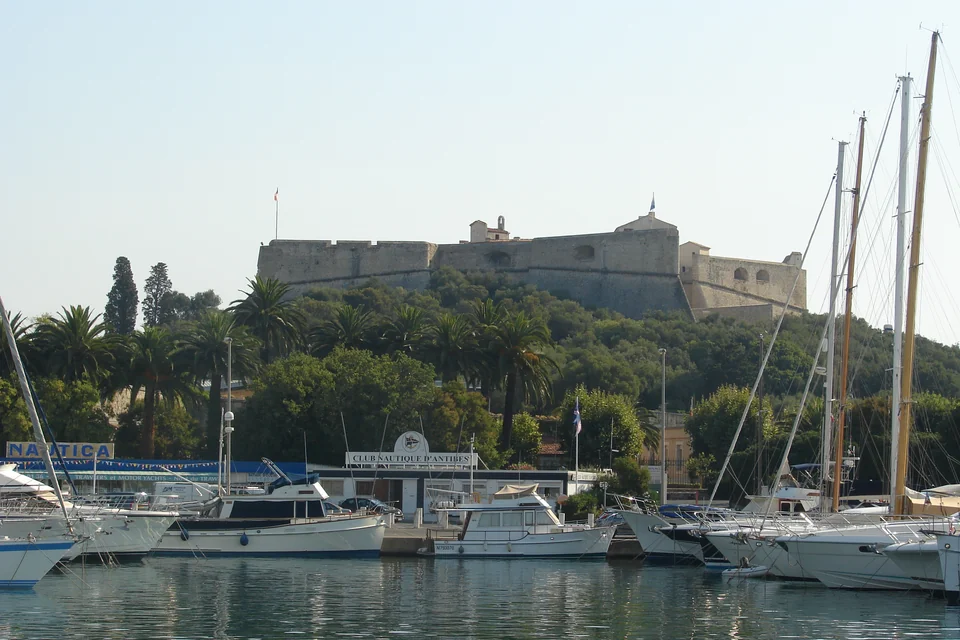 Sailing boats in Antibes harbour and the Fort Carré on the hill