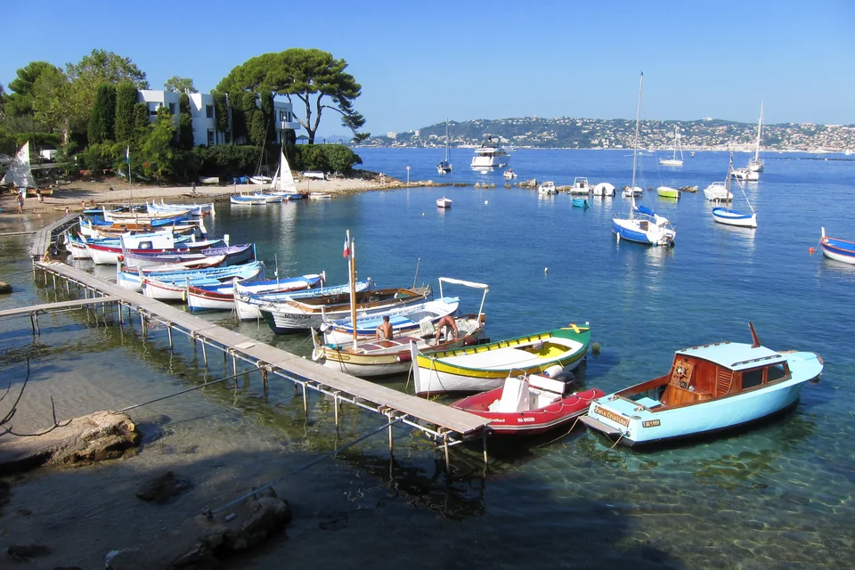 Colourful fishing boats tied to a wooden jetty in the Olivette cove, Antibes