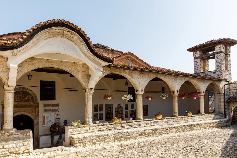 A historic Ottoman building with an arcaded portico and a cobbled courtyard in Berat