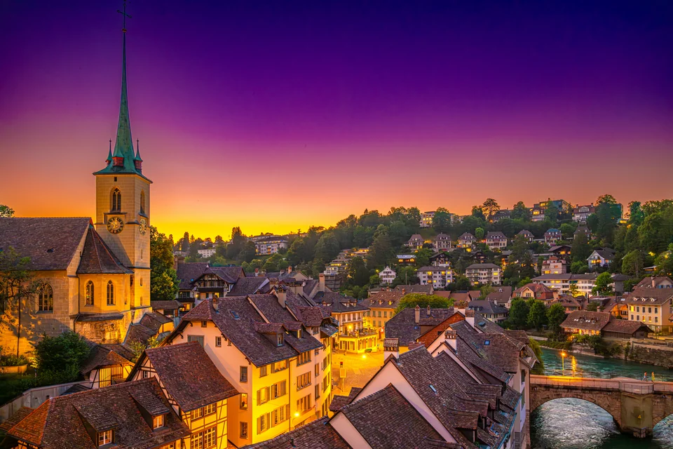 Old town rooftops and a spired church at sunset in Bern
