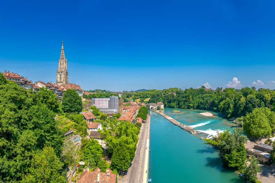 The turquoise Aare River, green banks and the cathedral tower in Bern