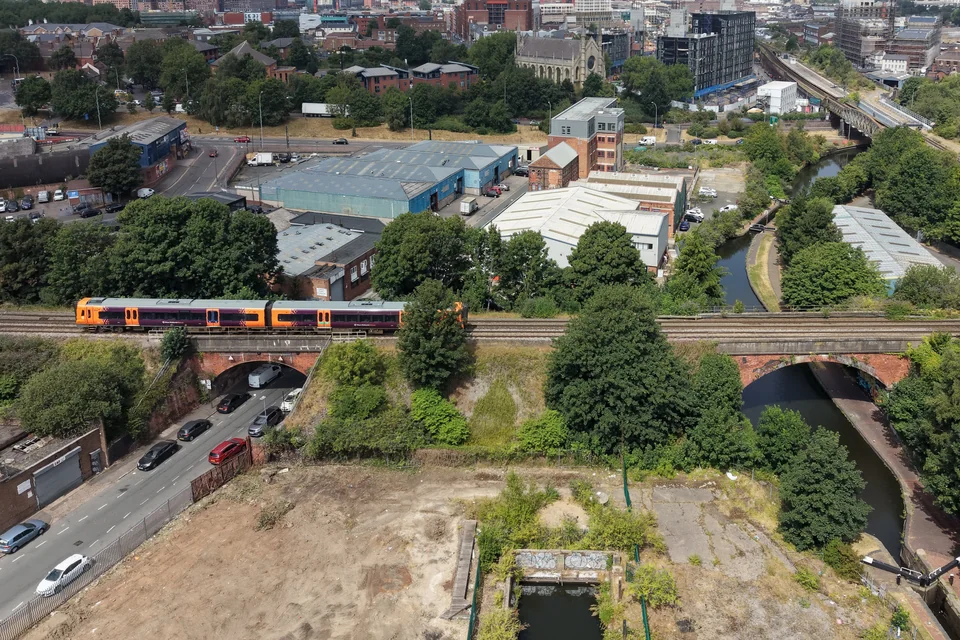 The canal and a railway bridge with the Birmingham city centre skyline behind