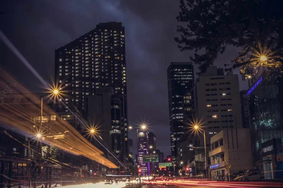 Lit high-rise towers and light trails along an avenue at night in Bogotá