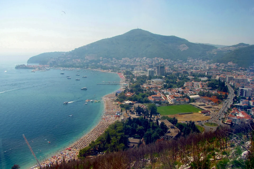 The beach curving along the bay, the town and the mountain behind Budva