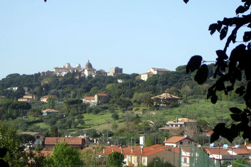 The Papal Palace and domed church on the hilltop above green slopes and houses, Castel Gandolfo