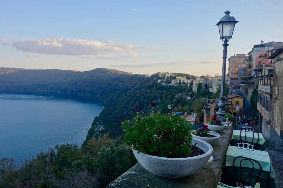 Flower-filled balconies and a lamp overlooking Lake Albano in Castel Gandolfo