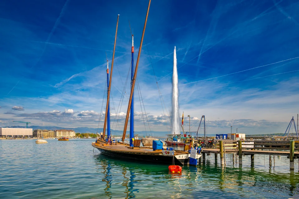A wooden sailing boat on Lake Geneva with the Jet d'Eau fountain behind