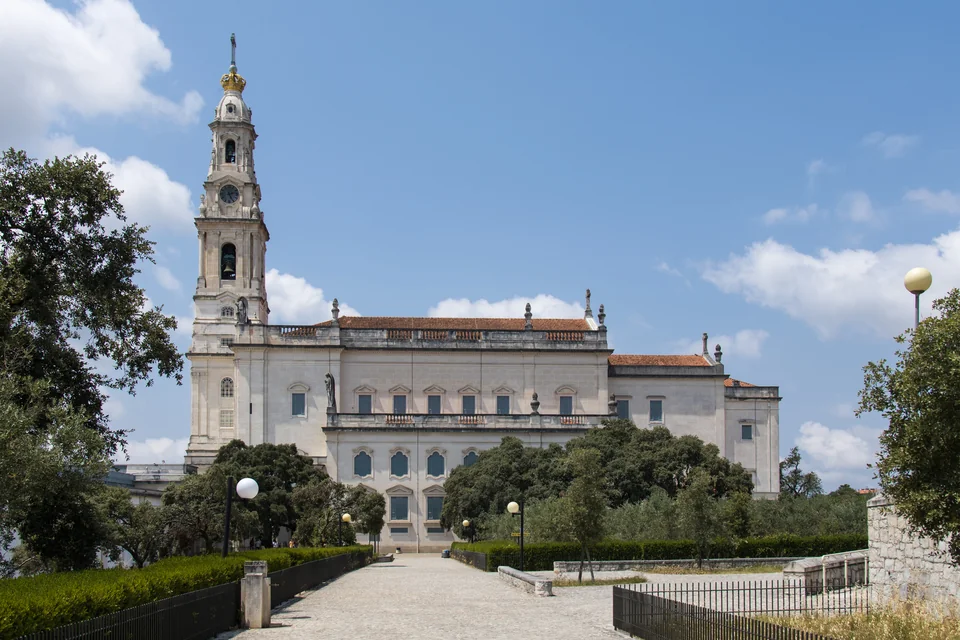 The towered Basilica of Our Lady of the Rosary seen through trees in Fátima