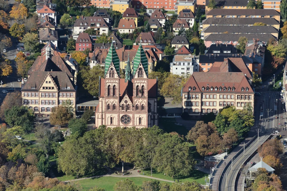 The twin-towered Sacred Heart Church and autumn trees seen from the air, Freiburg