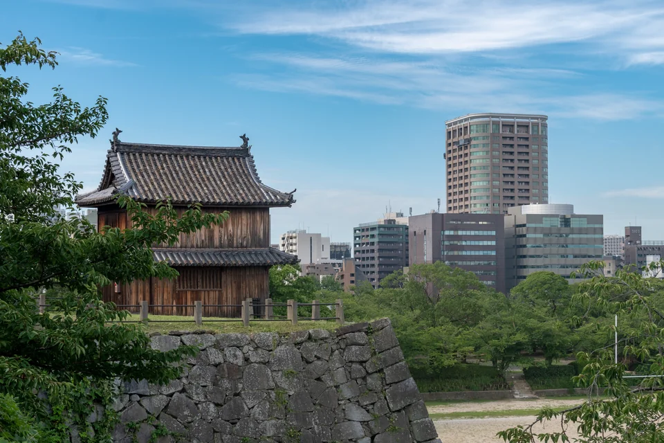 A wooden watchtower on the Fukuoka Castle walls with city buildings behind