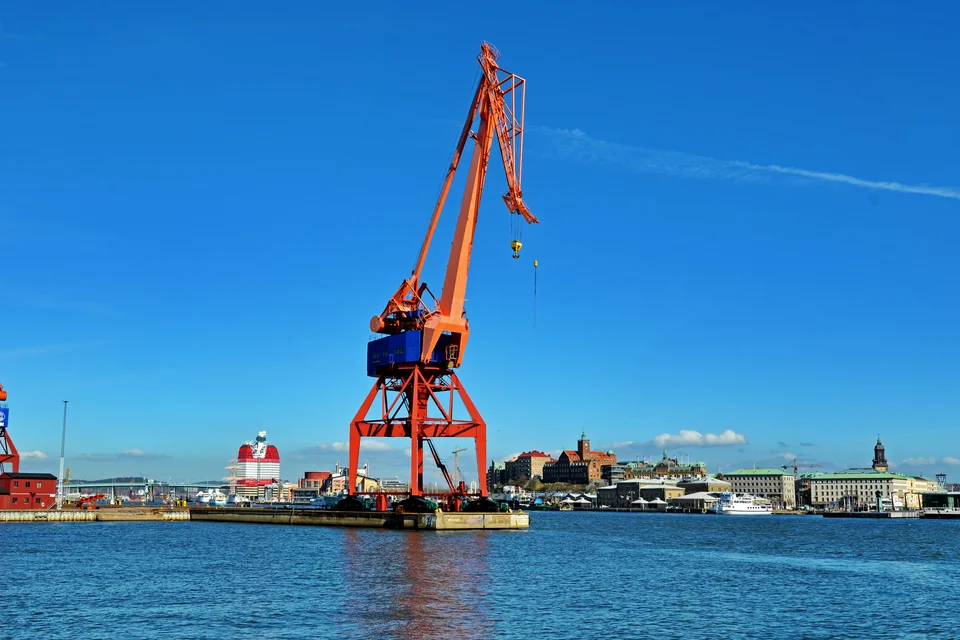 Orange historic cranes in Gothenburg harbour with the city on the shore