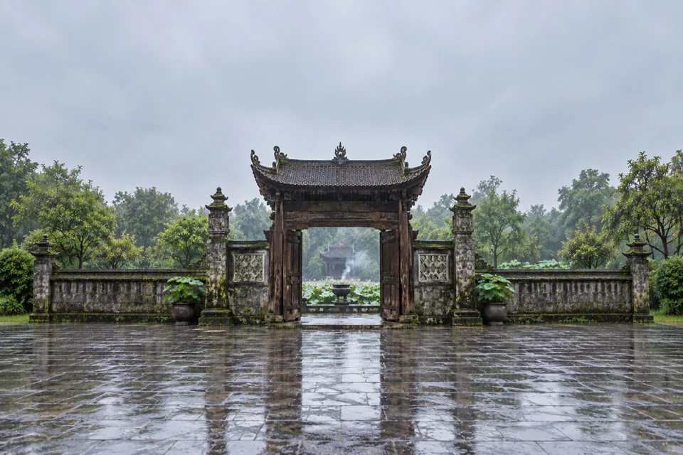 A wooden temple gate and a lotus pond in Hanoi