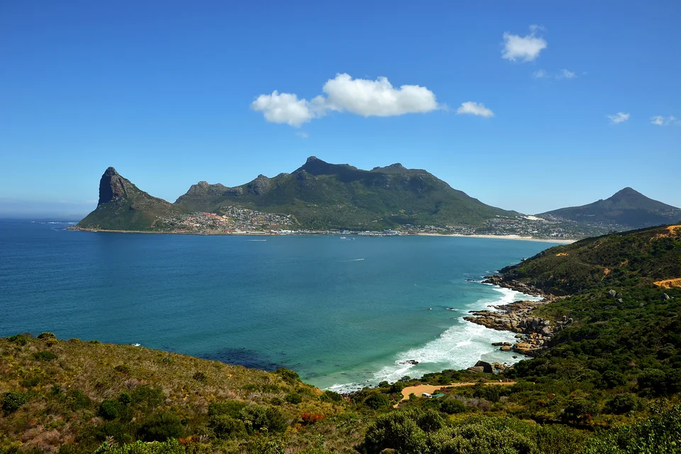 Hout Bay with its turquoise water, beach and the Sentinel and mountains behind