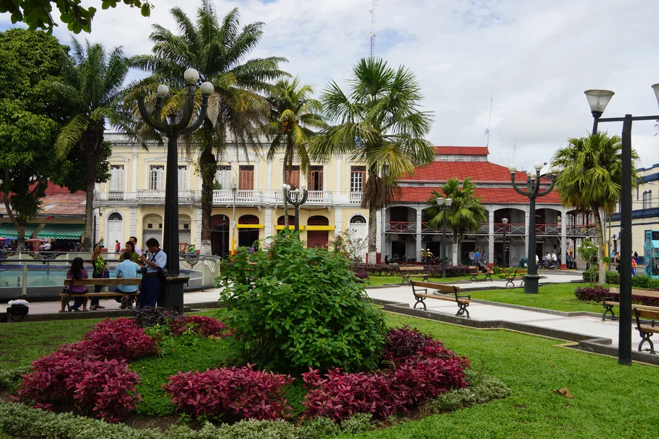 A flower garden, palms and historic buildings on the Plaza de Armas in Iquitos