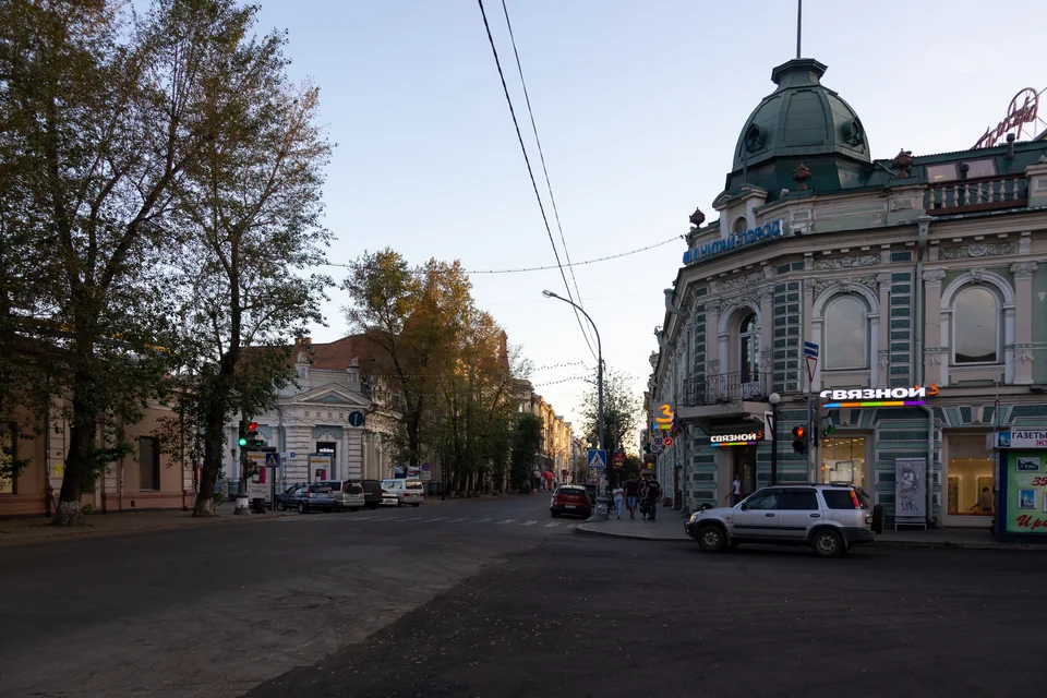 A green-domed historic corner building and autumn trees in Irkutsk