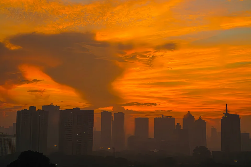 Skyscraper silhouettes under an orange sunset sky in Jakarta