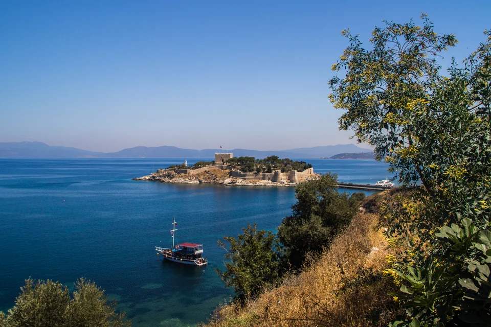 The Pigeon Island fortress, the blue Aegean and a wooden boat in the bay at Kuşadası