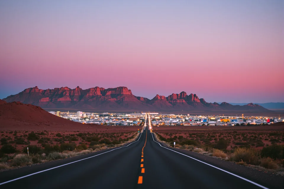 The desert road out of Las Vegas running to red rock hills at dusk