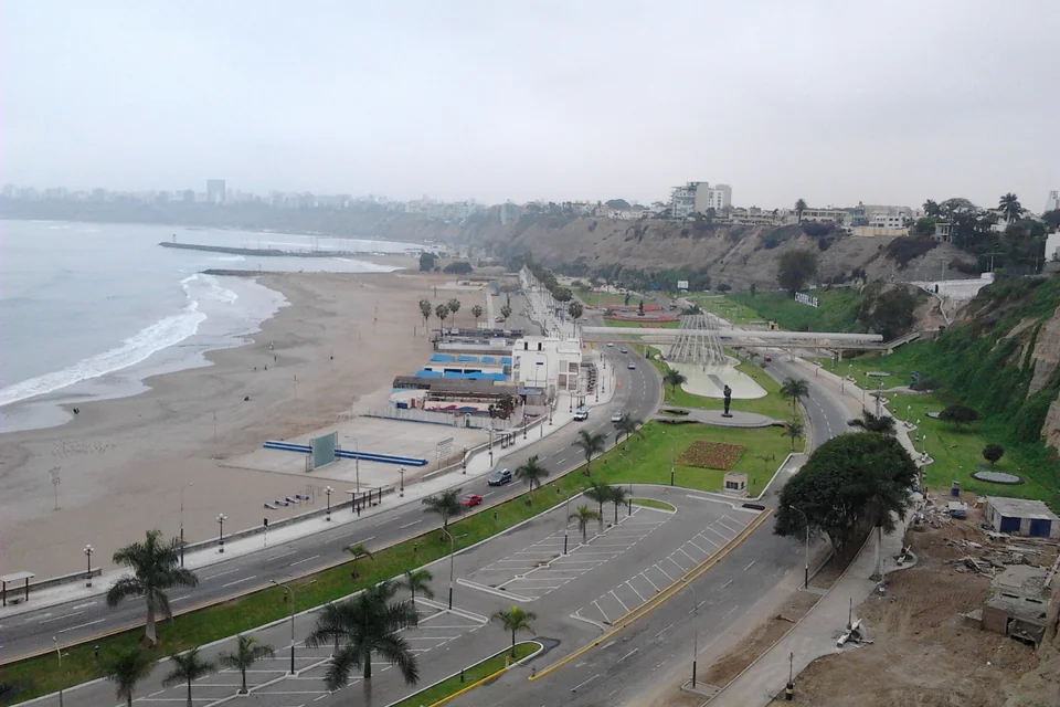 The beach, coastal road and green cliffs along the Pacific shore in Lima