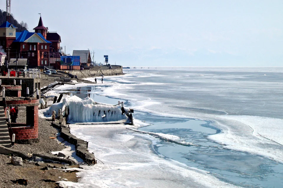 The ice-bound Baikal shore and timber houses in winter at Listvyanka