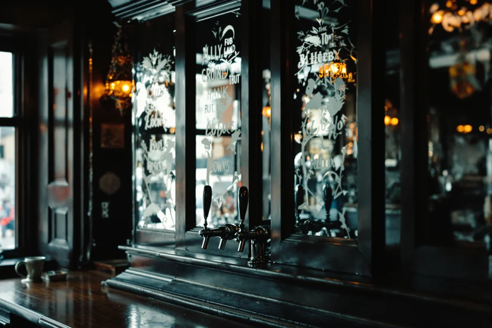 Dark wood and etched glass panels gleaming in the dim light of a London pub