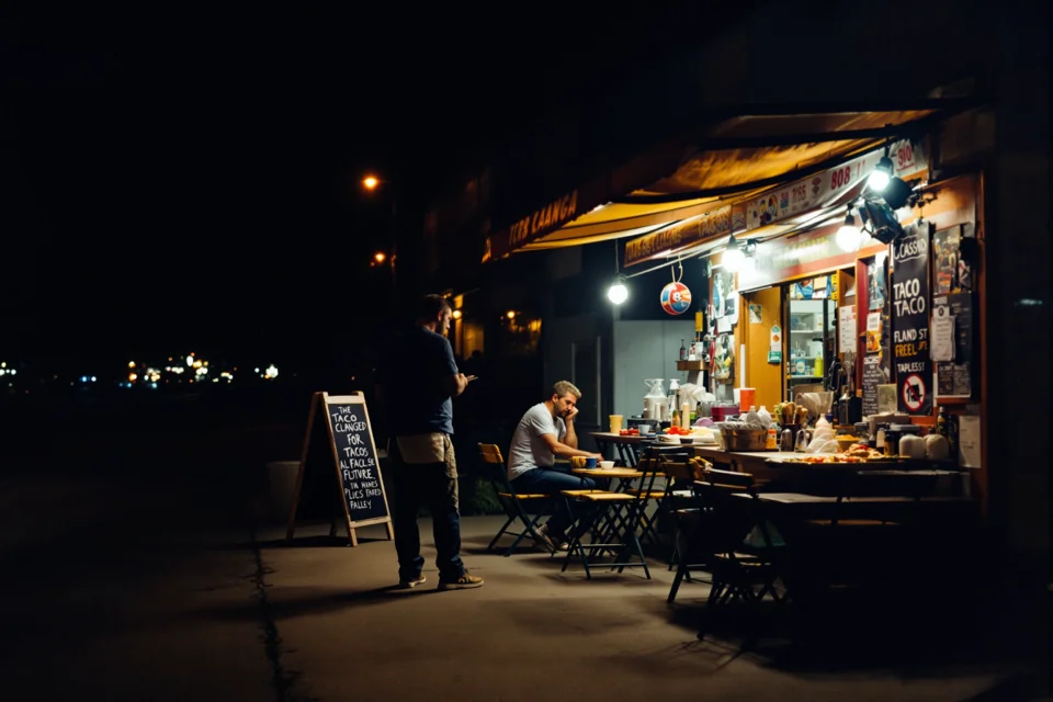 Los Angeles'ta açık hava taco tezgahında gece lamba ışığı altında masalar kuruluyor