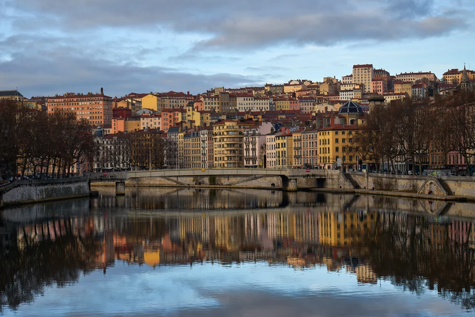 The colourful facades of Vieux Lyon and a stone bridge reflected in the Saône