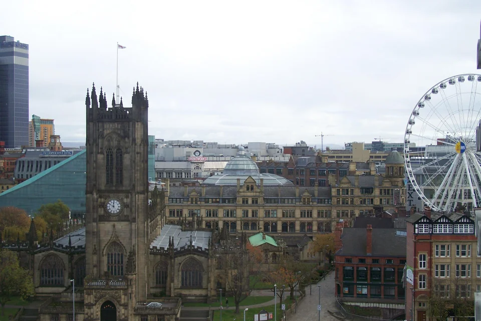 The Gothic Manchester Cathedral, a big wheel and city buildings