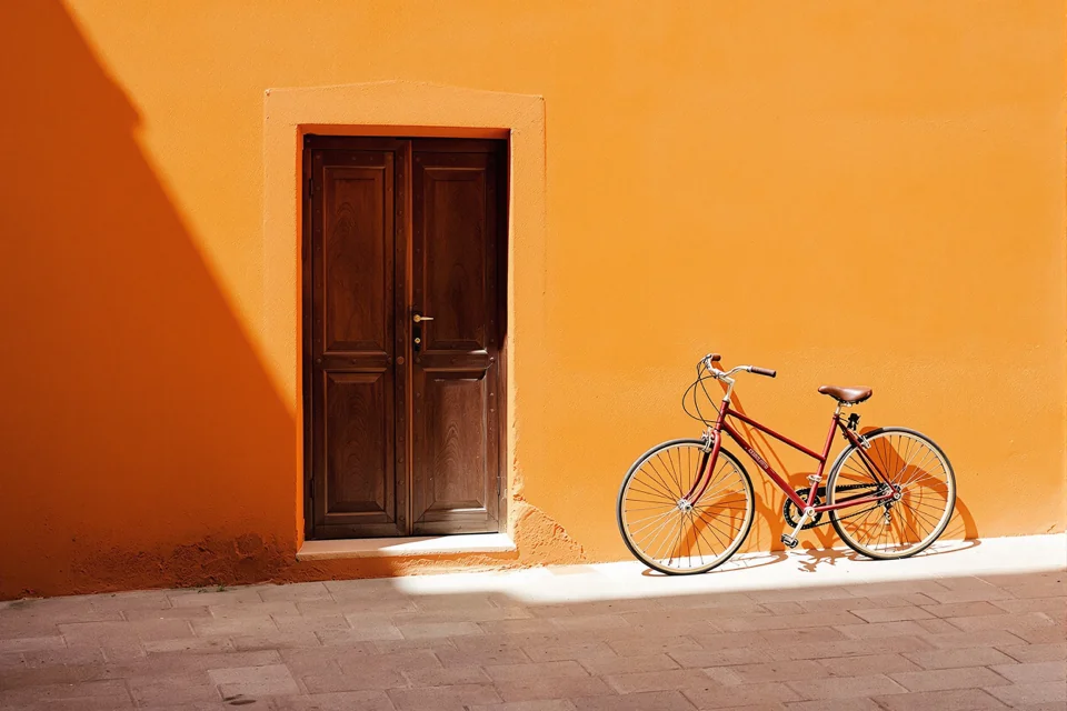 A bicycle leaning on the wall by a wooden door on an orange-washed street in Marrakesh