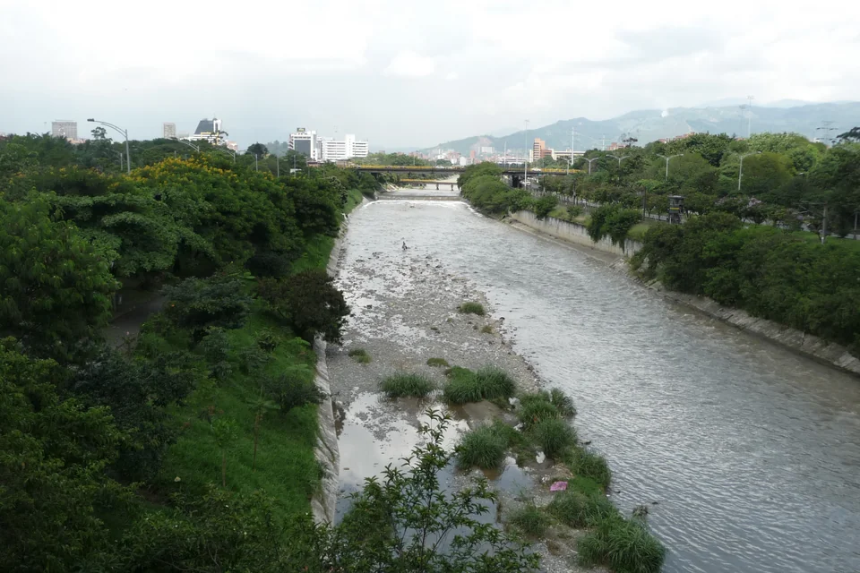 The Medellín River flowing between green banks with mountains in the distance