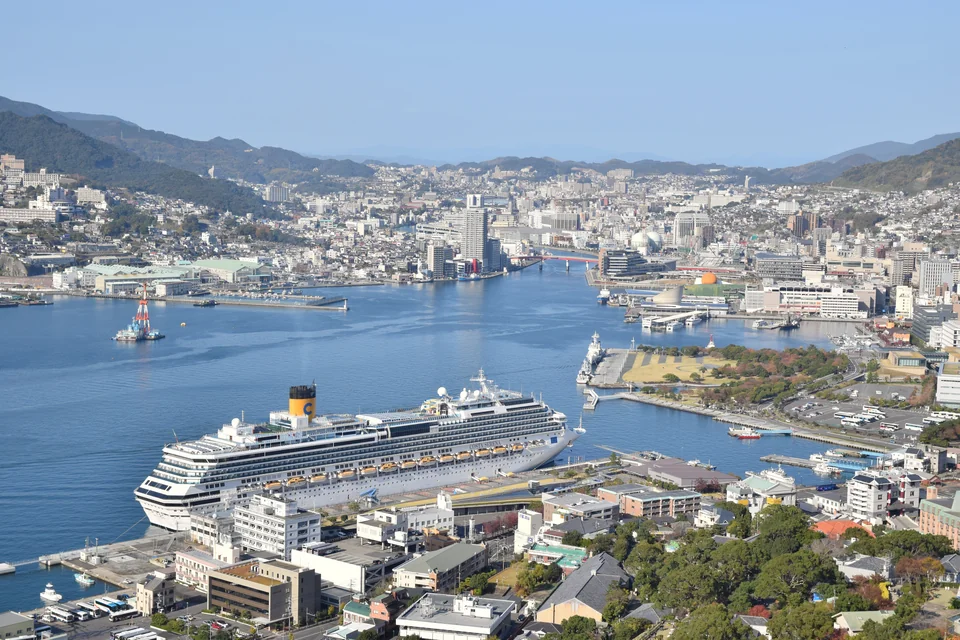 An aerial view of Nagasaki harbour, a cruise ship at the quay and the city on the hills