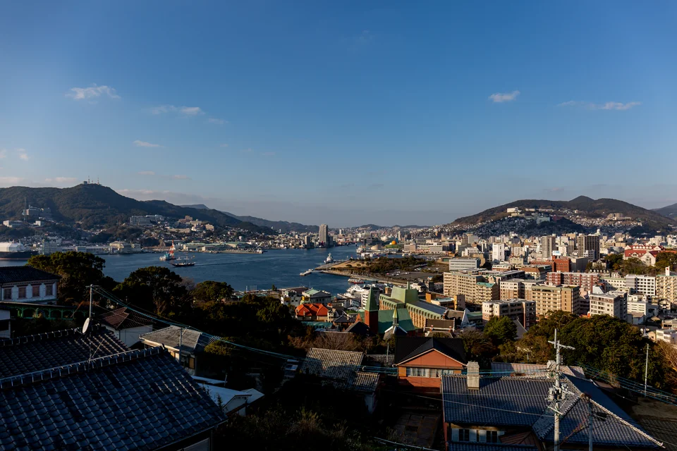 The harbour mouth and the city spreading over the slopes, seen from a hill in Nagasaki