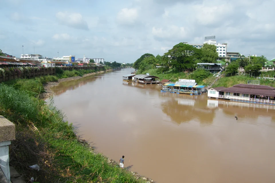 The Nan River flowing between green banks with floating houses in Phitsanulok
